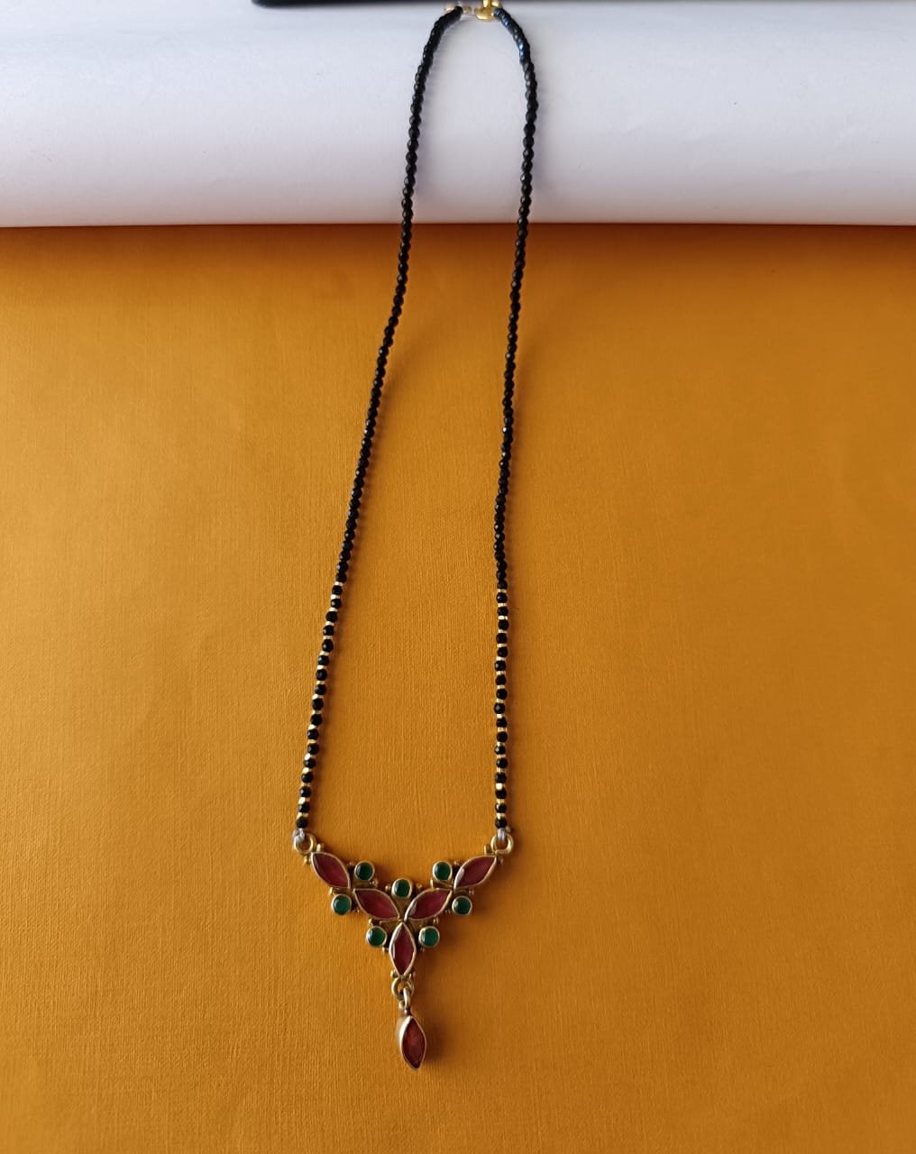 Red and green stones with gold polish pendent with black beads chain single line